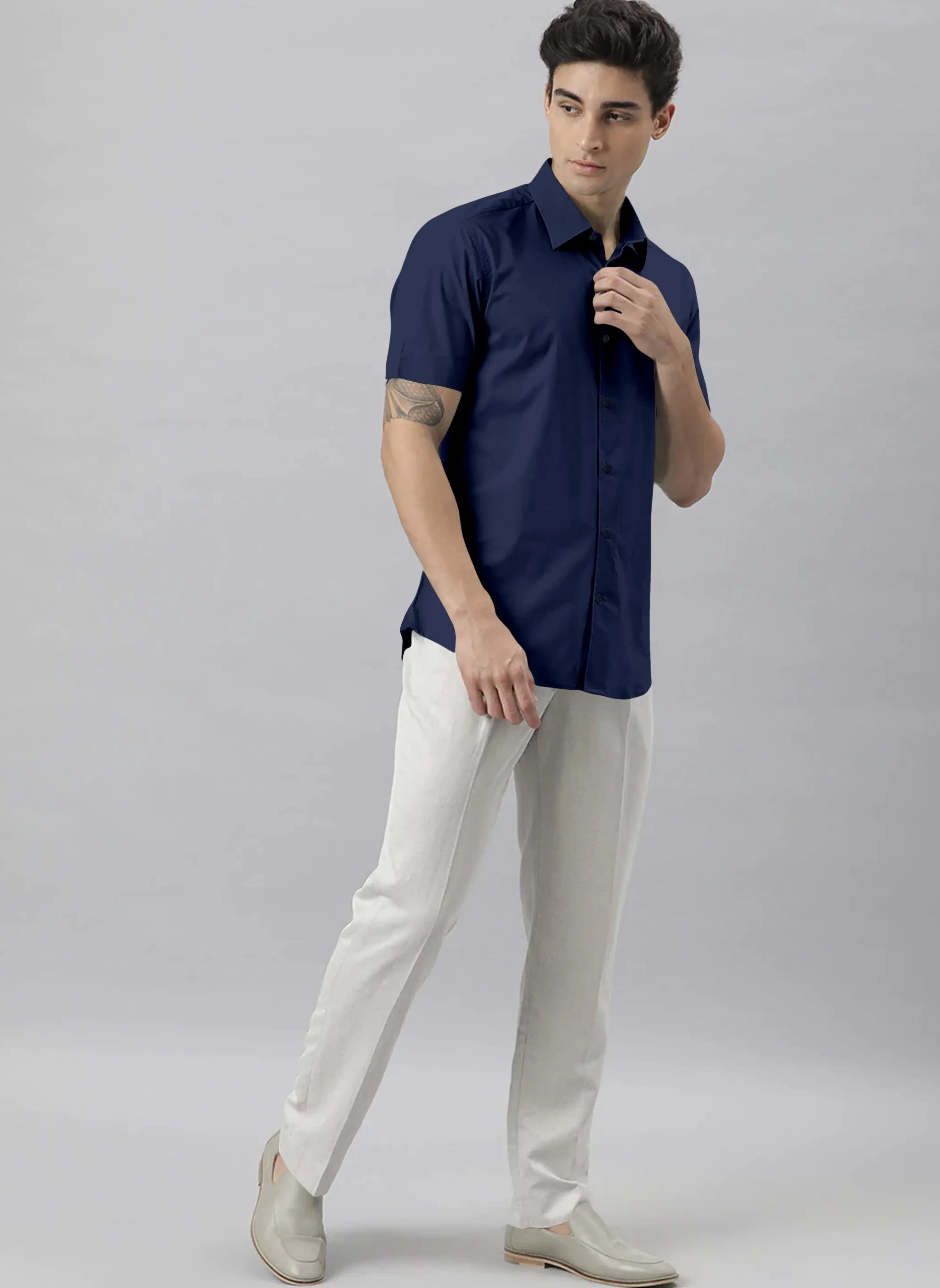 Man wearing a navy shirt and white pants against a gray background