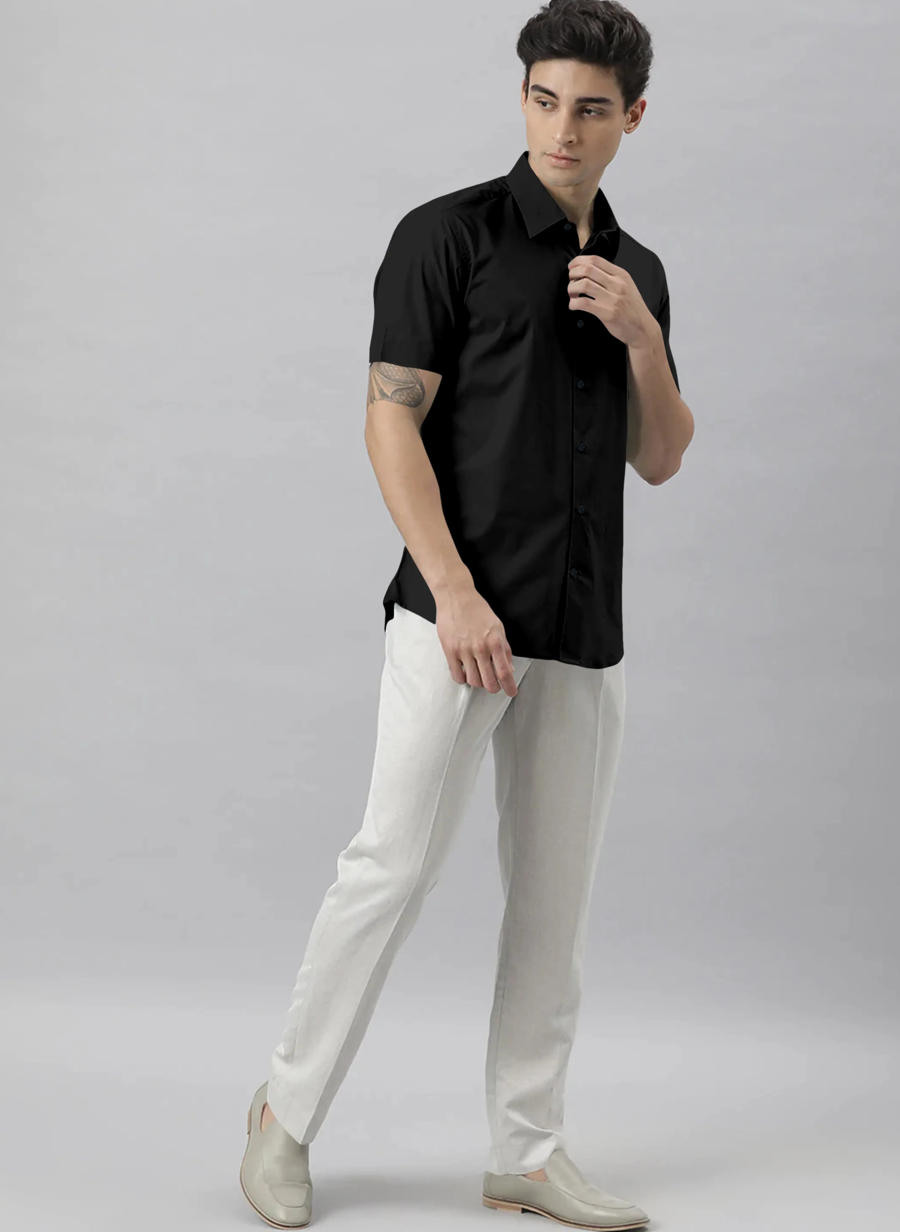Man wearing a black shirt and white pants against a gray background