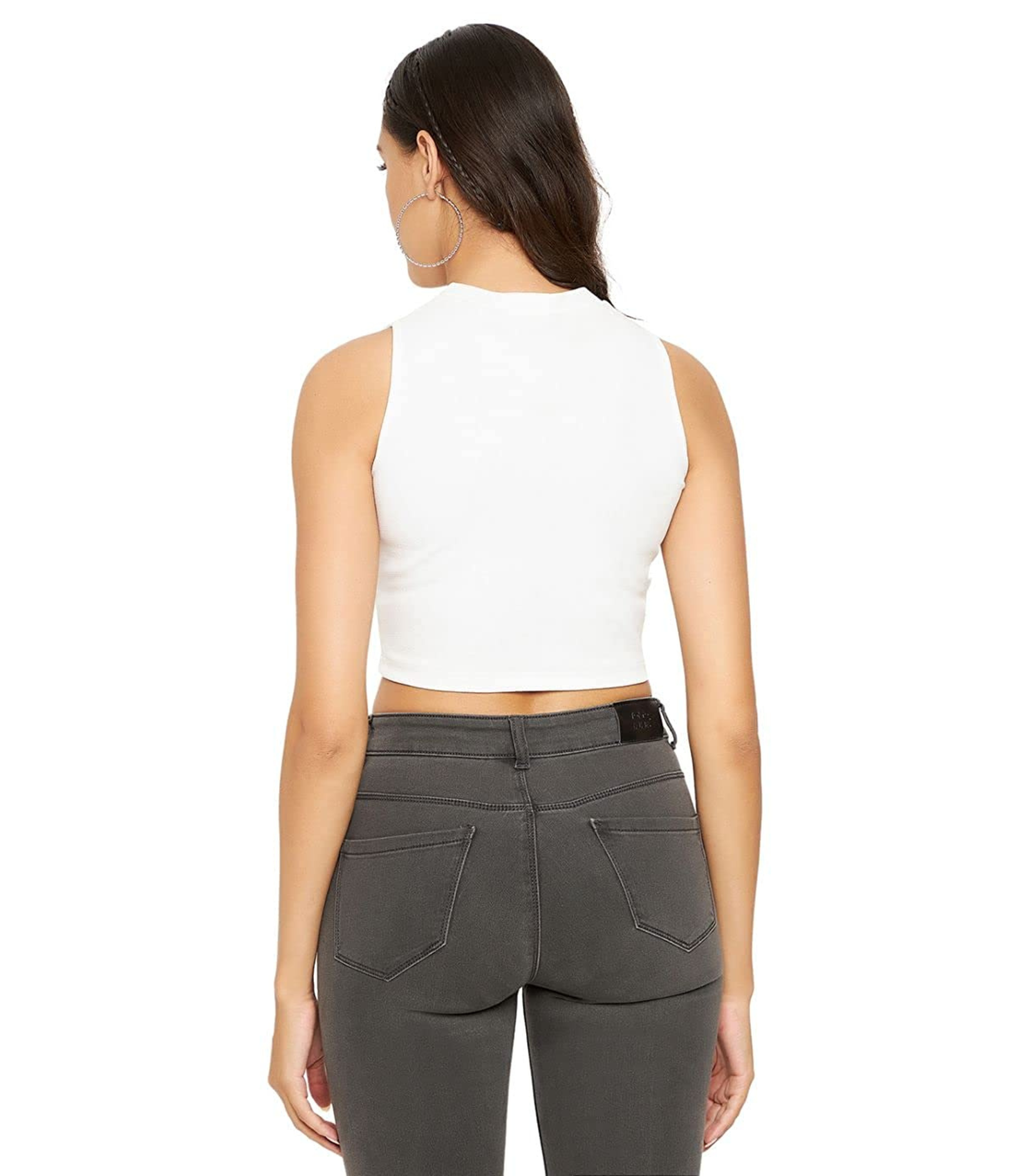 Woman wearing a white sleeveless top and gray pants on a white background
