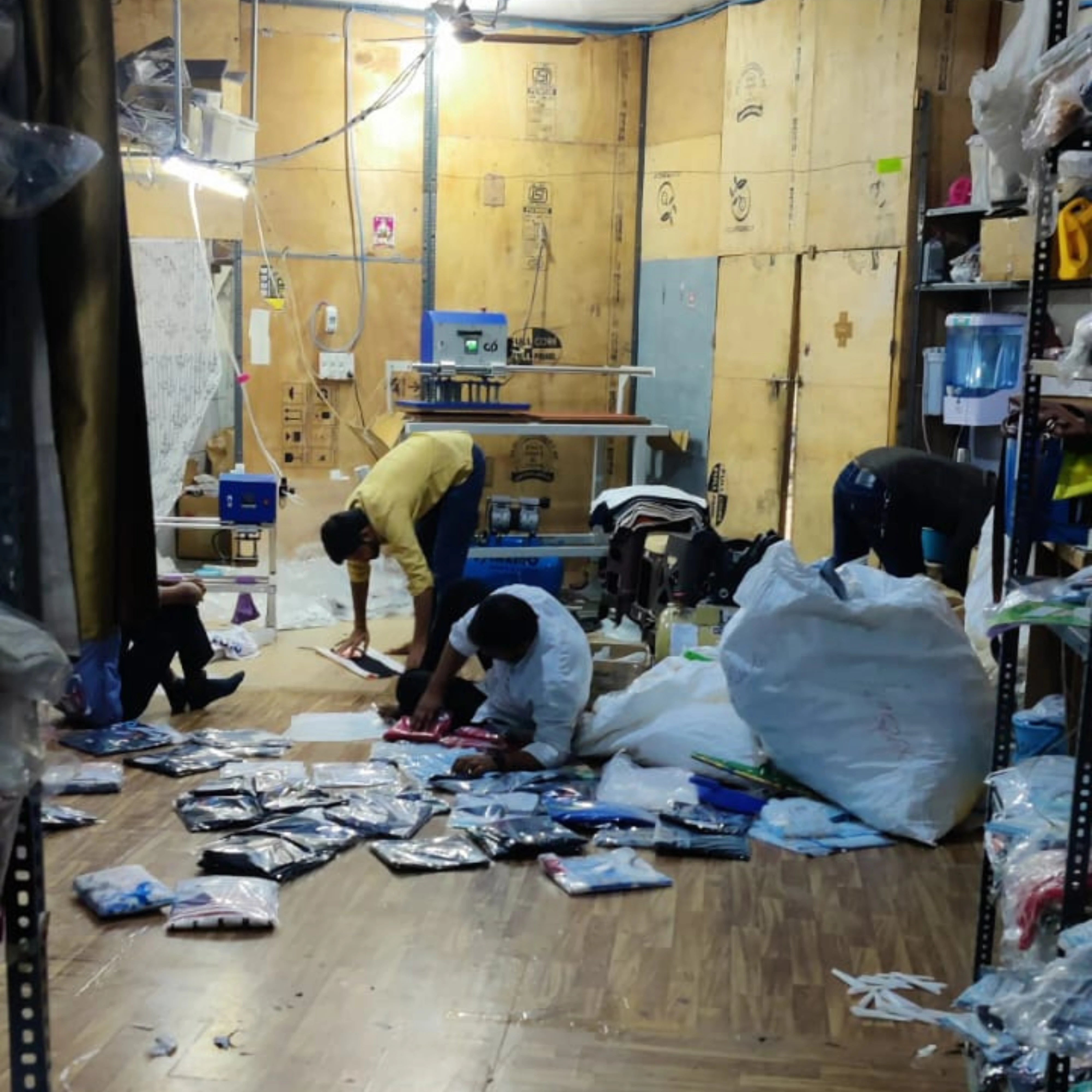People working in a warehouse with boxes and equipment on the floor.
