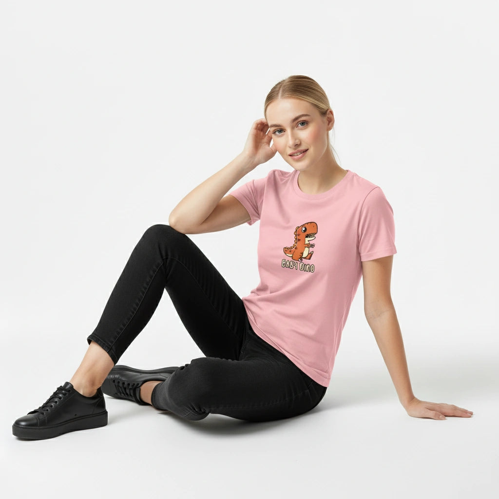 Woman wearing a pink t-shirt with a dinosaur graphic and text, sitting on a white background