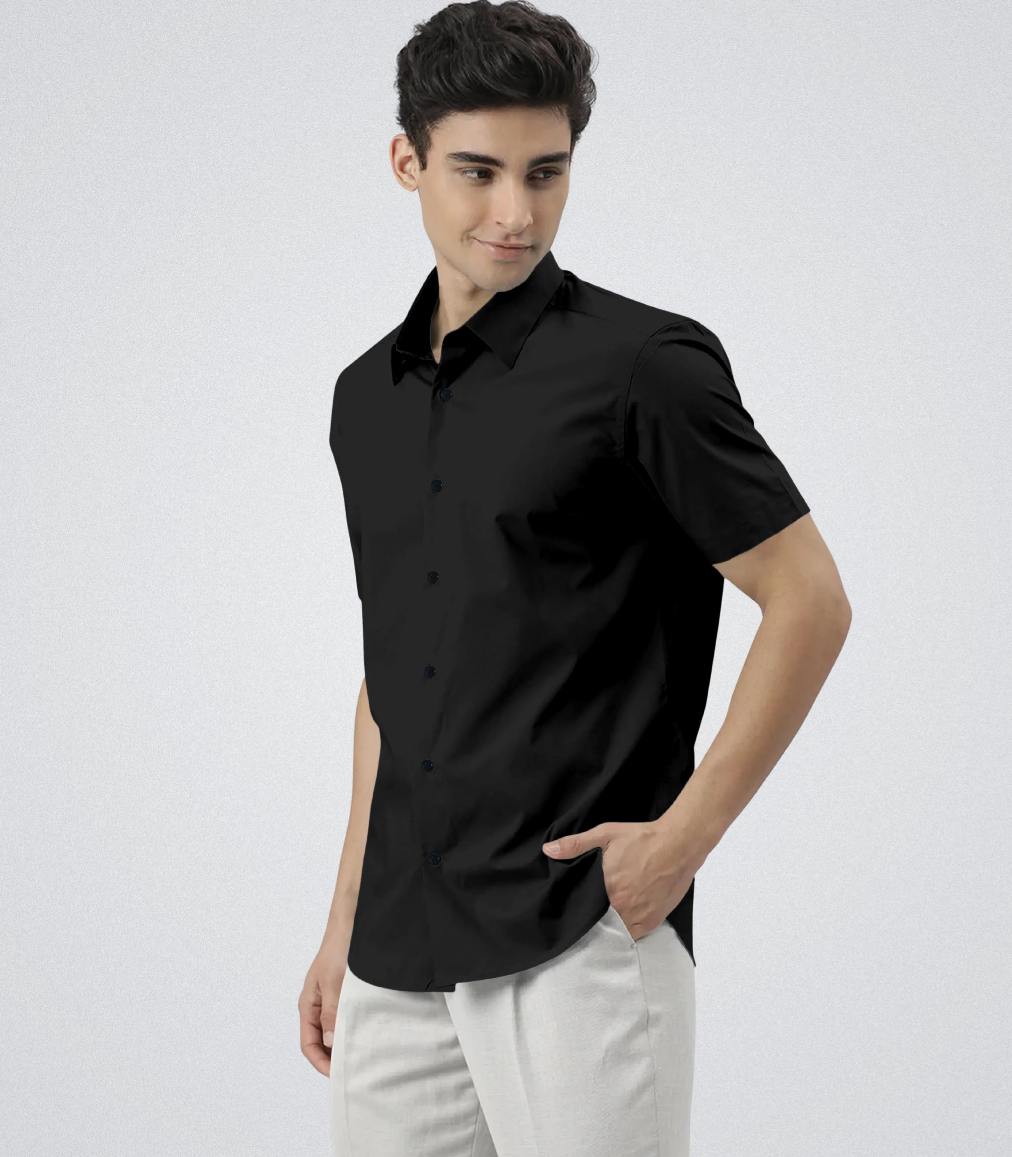 Man wearing a black short-sleeve shirt and white pants on a light gray background