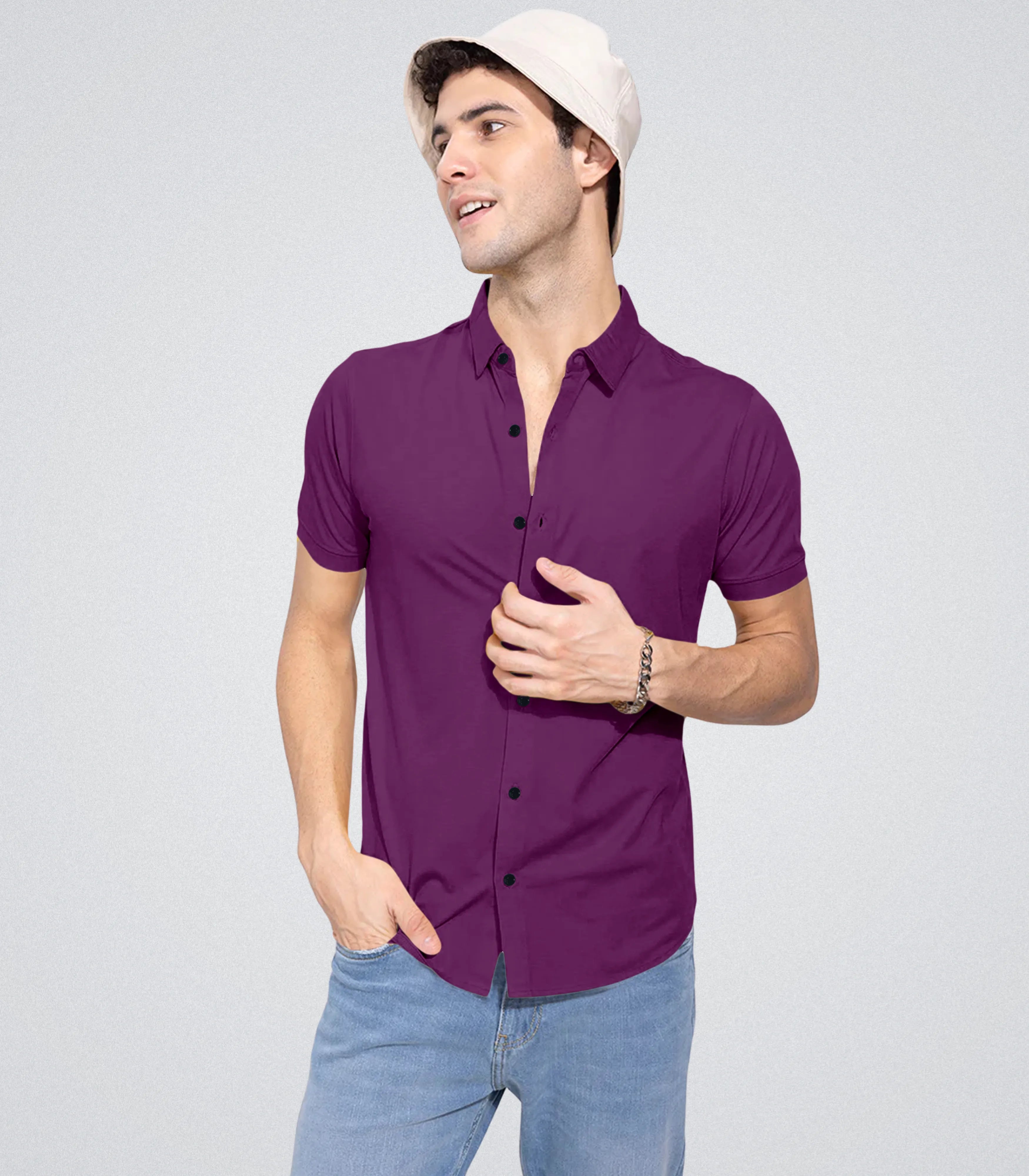 Man wearing a purple shirt and light blue jeans on a gray background