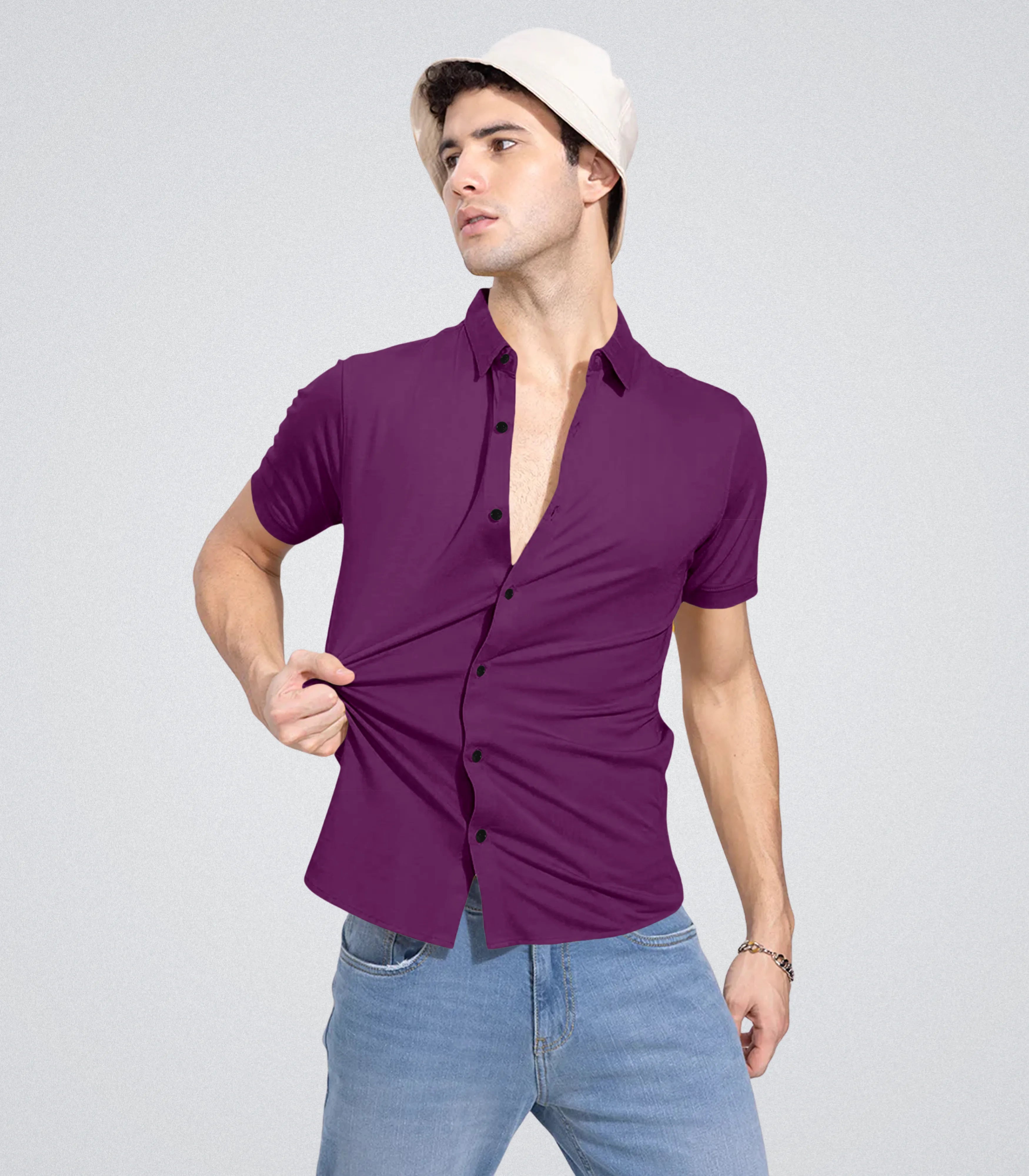 Man wearing a purple shirt and light blue jeans against a gray background