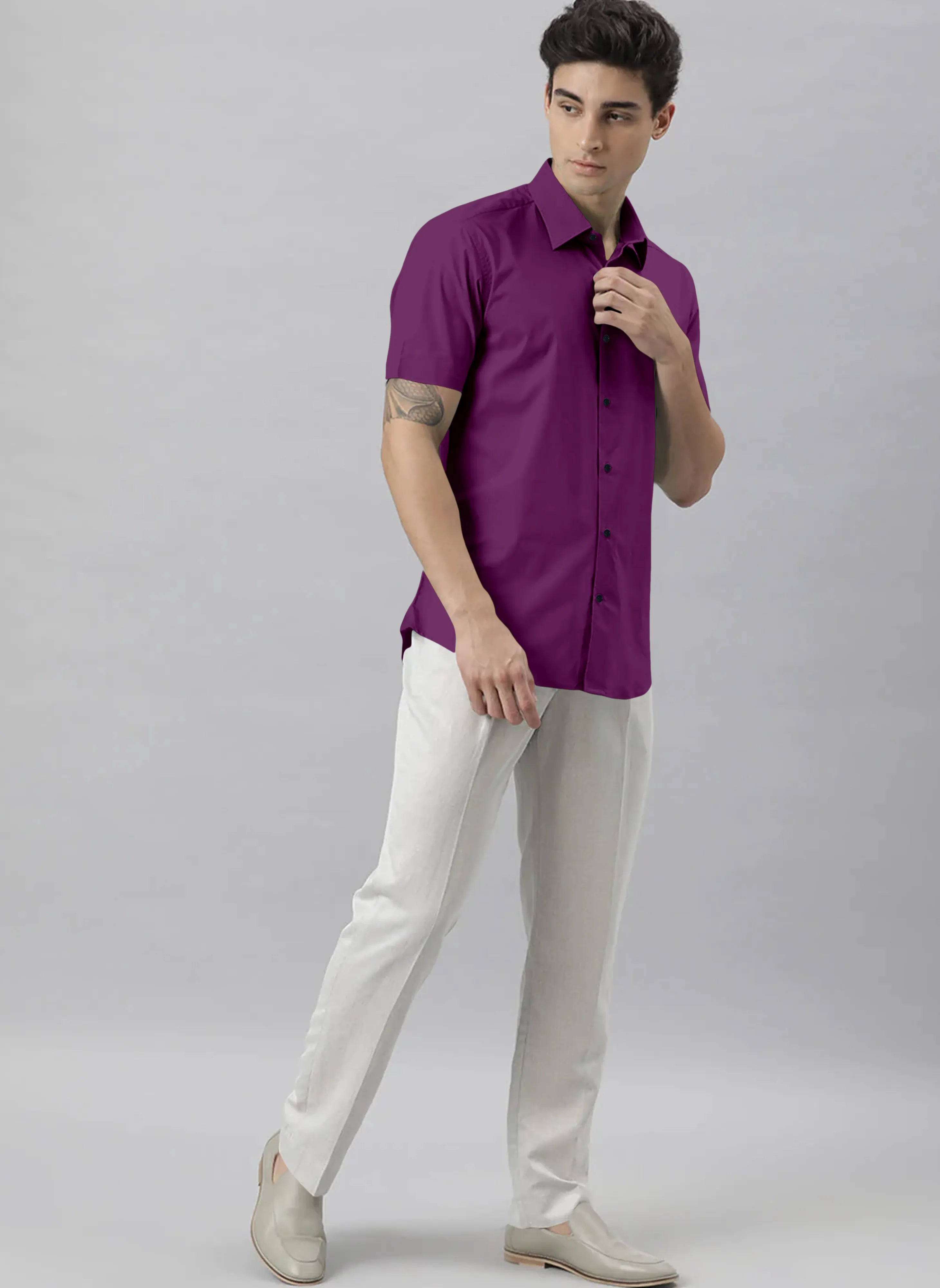 Man wearing a purple shirt and white pants on a gray background