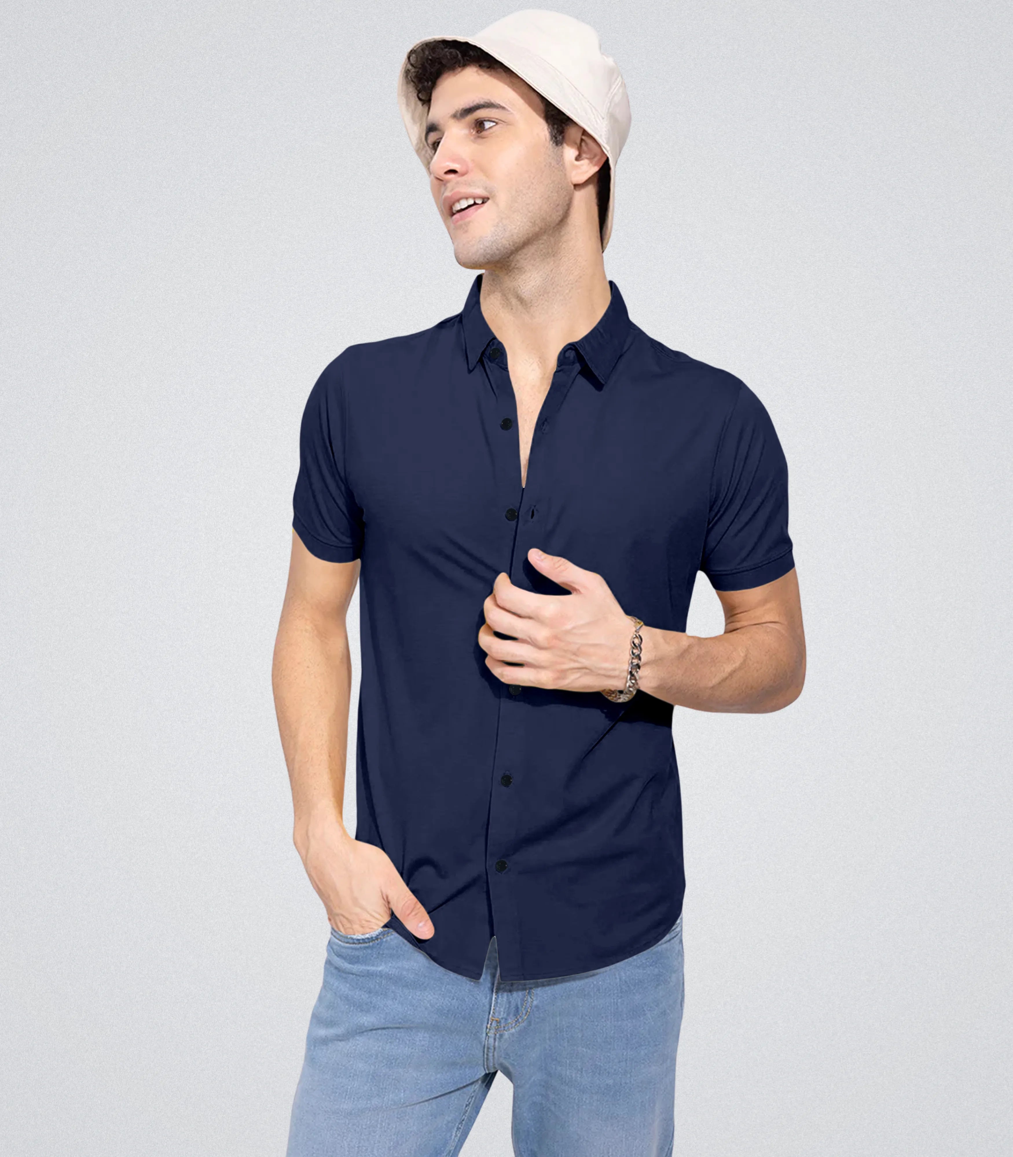 Man wearing a navy blue shirt and light blue jeans on a gray background