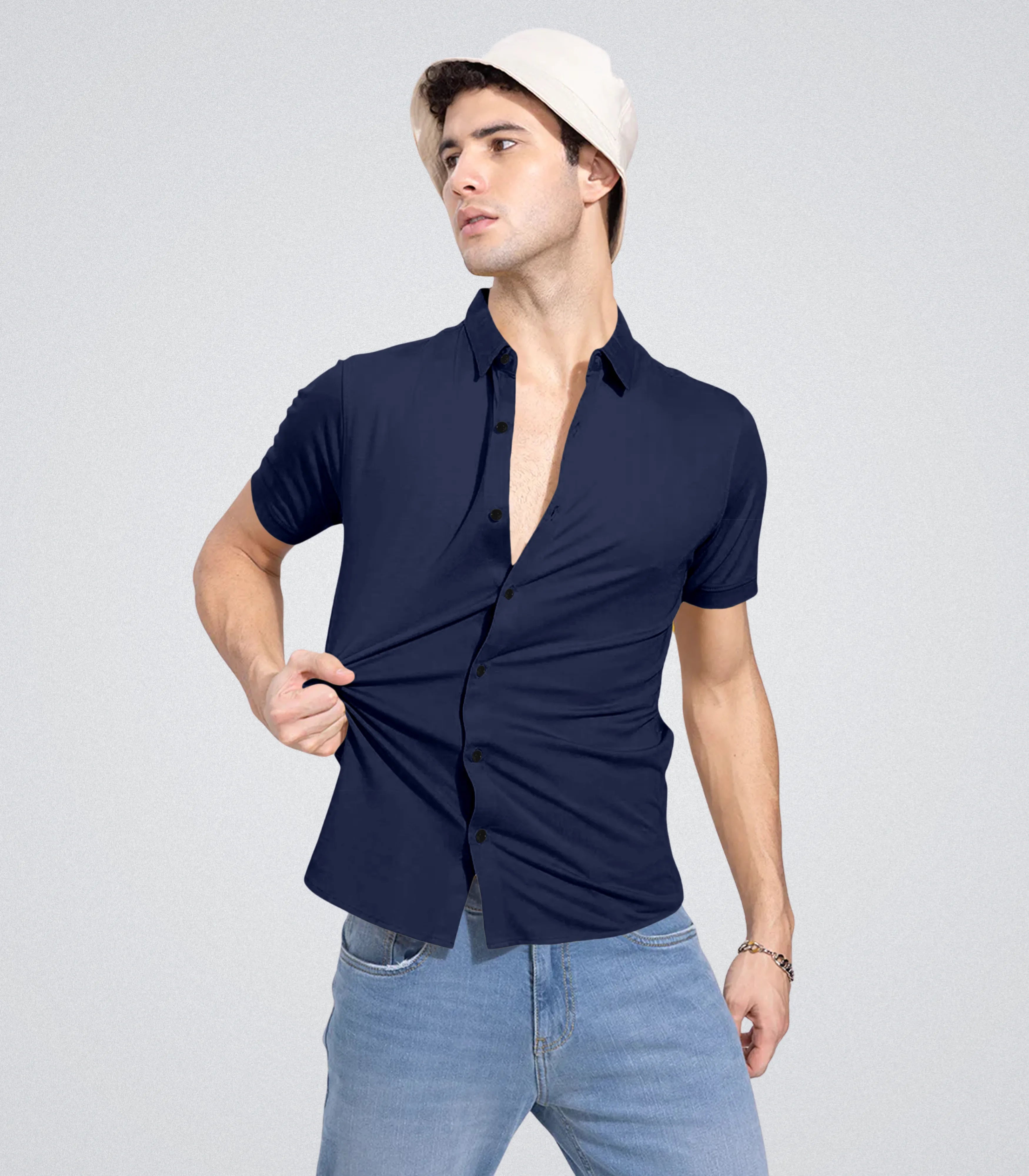 Man wearing a navy blue shirt with the top button undone, standing against a plain background