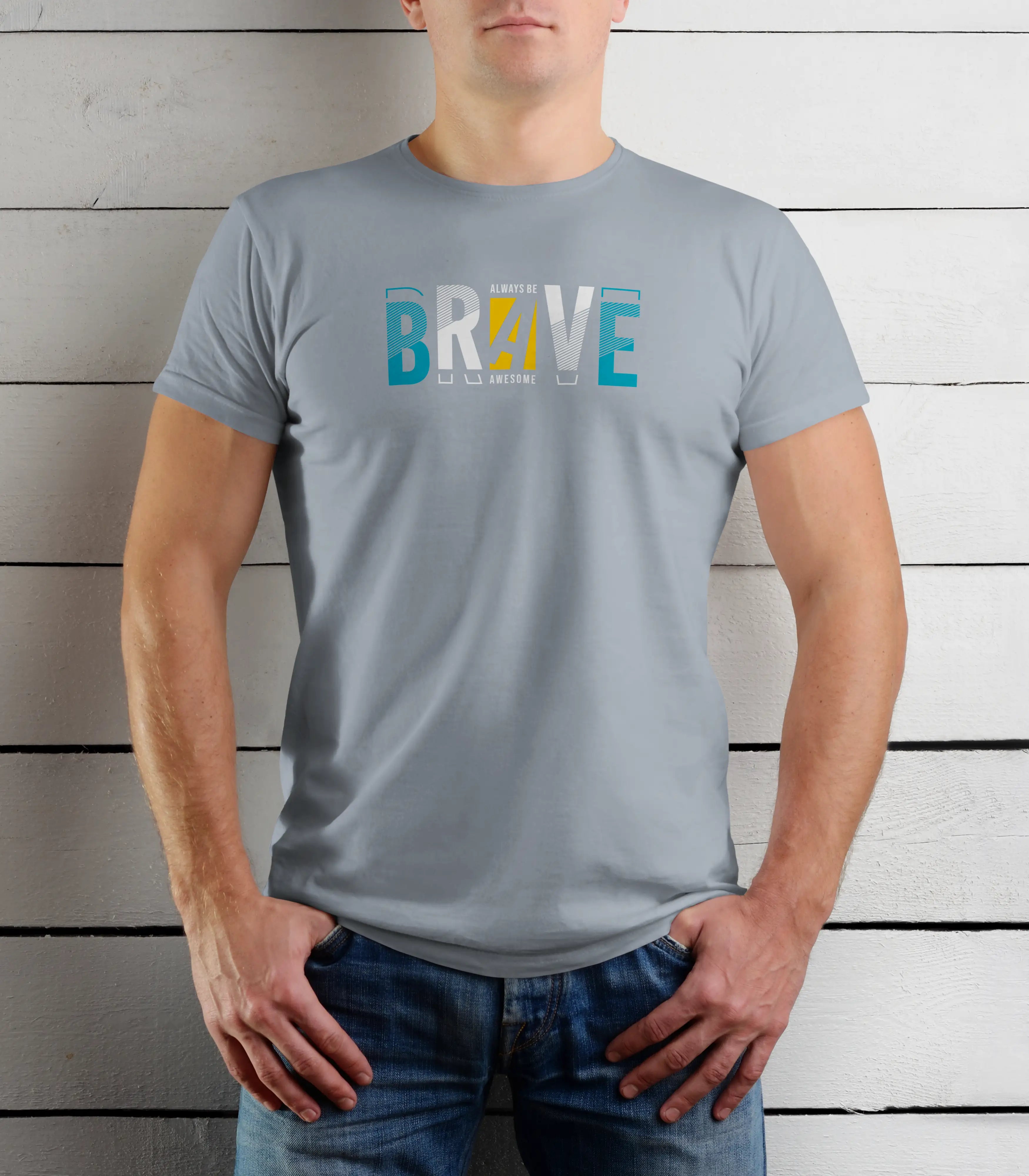 Person wearing a gray t-shirt with colorful text 'BRAVE' against a wooden background