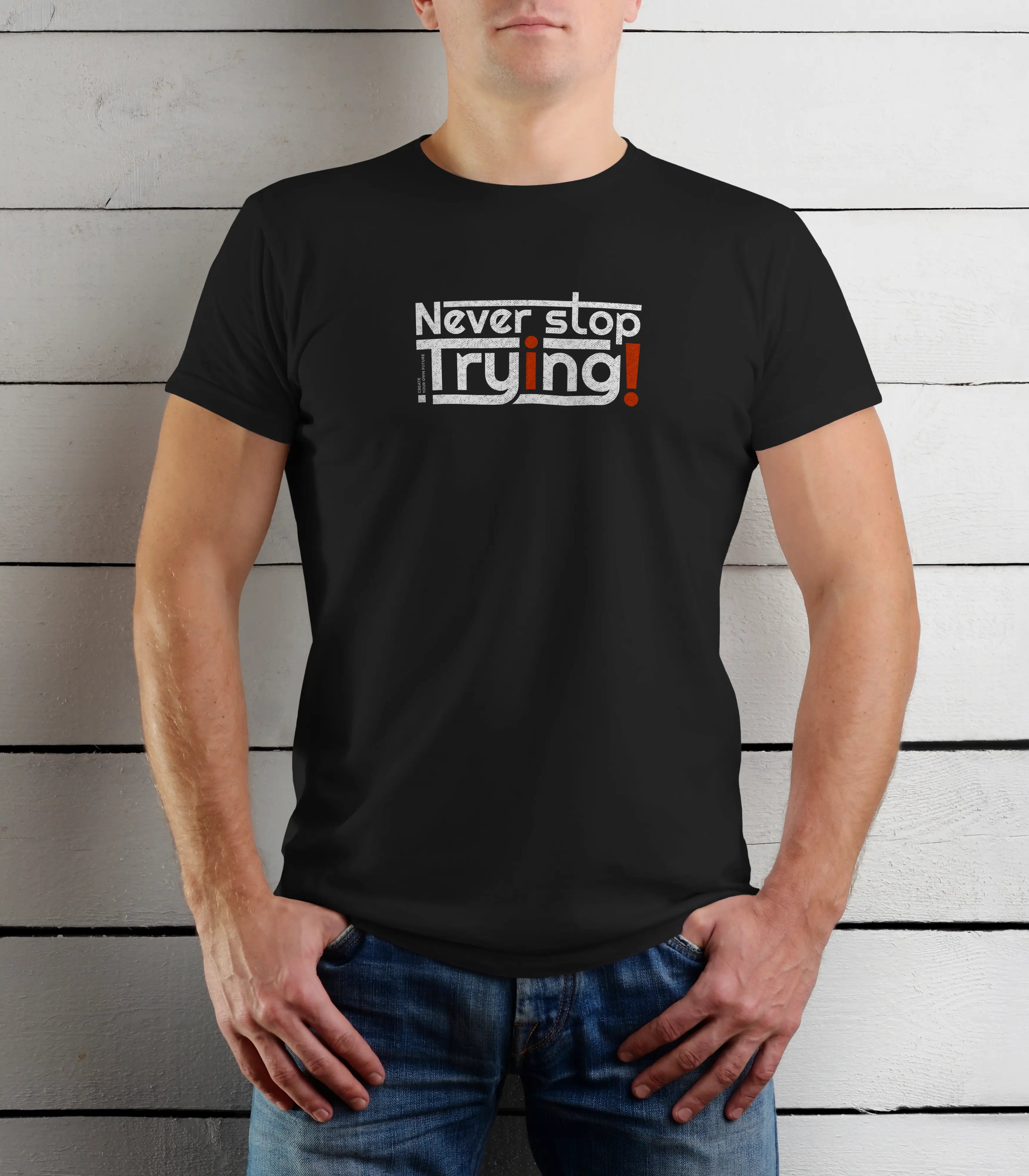 Person wearing a black t-shirt with 'Never stop trying' text against a wooden background